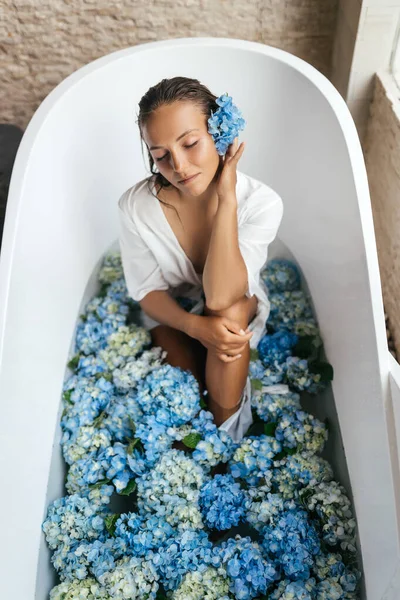 Nő relaxáló fürdőben trópusi kék hortenzia. — Stock Fotó