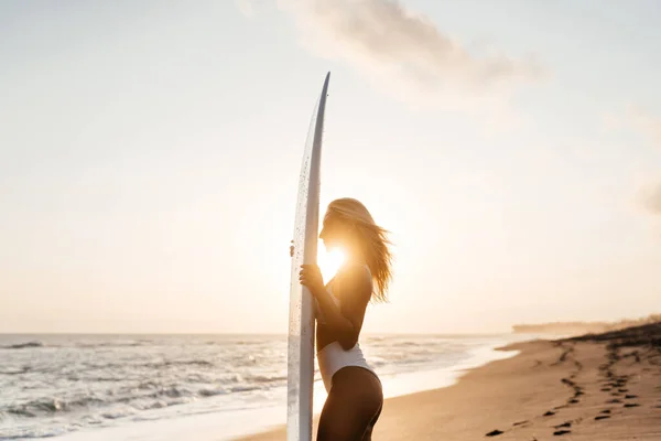 Mooie surfer vrouw op het strand bij zonsondergang — Stockfoto