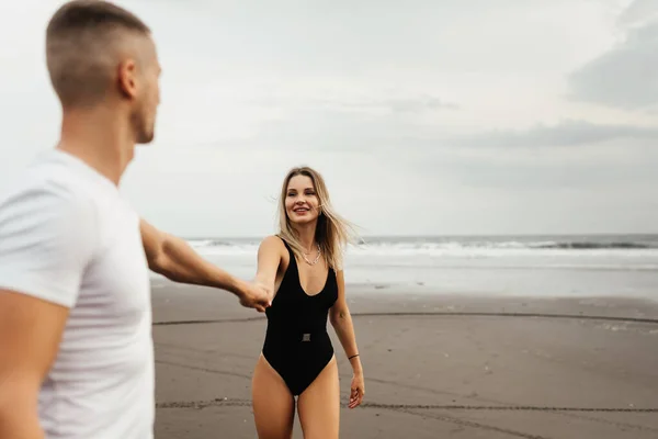 Utomhus bild av leende unga par promenader på stranden. — Stockfoto