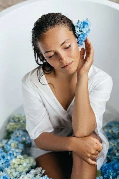Frau entspannt sich im Bad mit tropischen blauen Hortensien. — Stockfoto