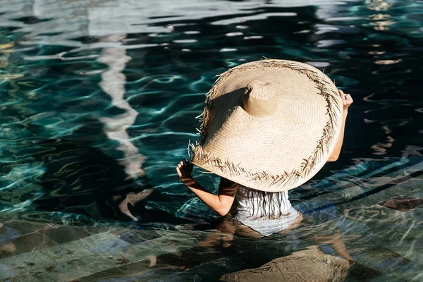Donna in grande cappello di paglia rilassante in piscina. — Foto Stock