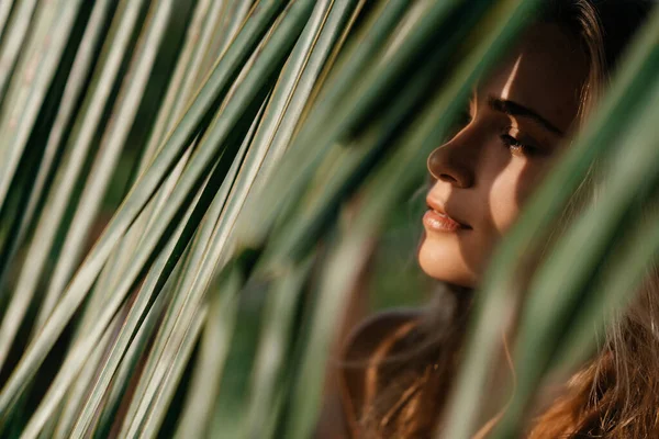 Портрет нежной женщины, выглядывающей из пальмового листа — стоковое фото