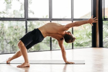 Yogacı adamlar stüdyoda pencerenin önünde egzersiz yapıyor.