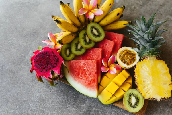 Tropische Früchte auf einem Holzteller. Steinhintergrund. — Stockfoto