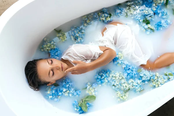 Frau entspannt sich im Bad mit tropischen blauen Hortensien. — Stockfoto