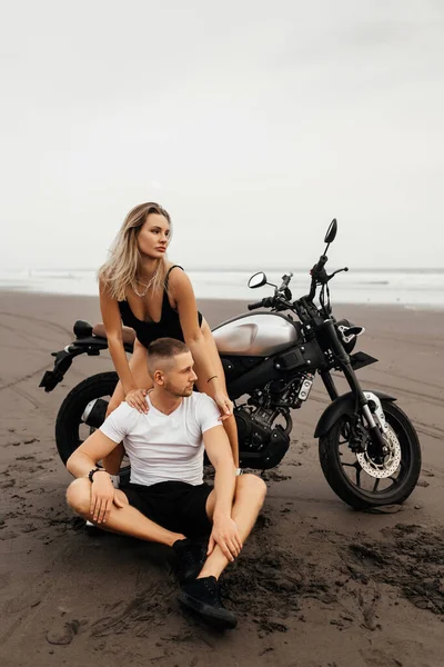 Unga par ryttare tillsammans på sandstrand med motorcykel — Stockfoto