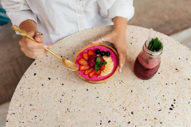 Bronz tenli kadın Bali 'de tatilde dinleniyor ve kahvaltıdan zevk alıyor.