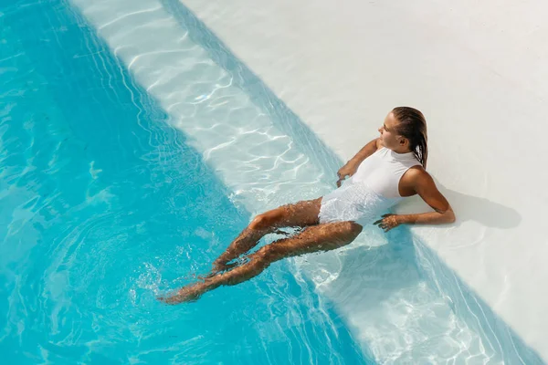 Young woman relaxing in swimming pool on summer vacation.