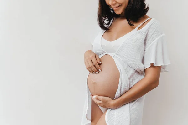 妊娠中の女性は白い背景で腹に手を保持します. — ストック写真