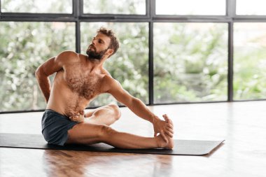 Yogacı adamlar stüdyoda pencerenin önünde egzersiz yapıyor.