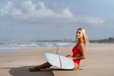 Uzun sarı saçlı sörfçü kadın okyanusa gider..