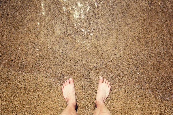 Gambe dell'uomo sulla spiaggia di sabbia e onde del mare Immagine Stock