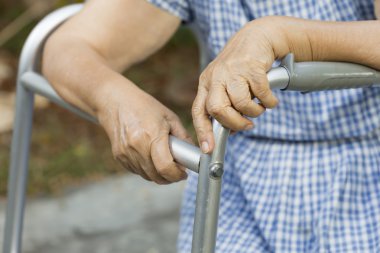 Walker ile arka bahçesinde oturan yaşlı.