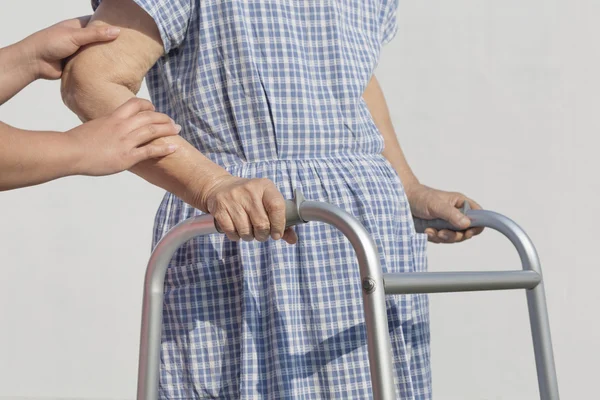 Senior vrouw met behulp van een walker met verzorger — Stockfoto