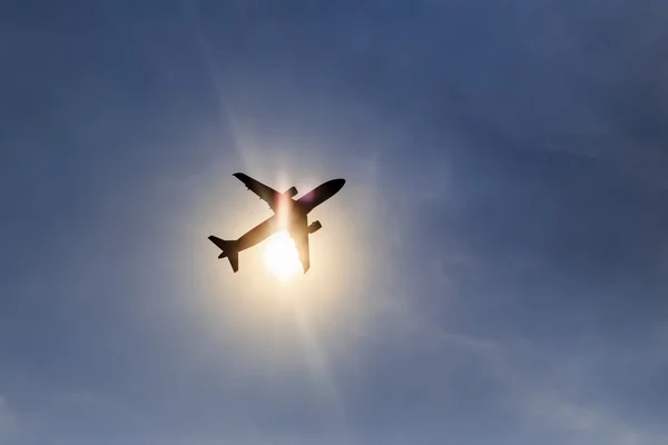 Silueta avión despegando sobre el cielo azul en el fondo del sol —  Fotos de Stock