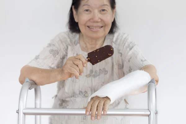 Bejaarde vrouw gebroken pols genieten van ijs — Stockfoto