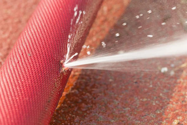 Water leaking from hole in a hose — Stock Photo, Image