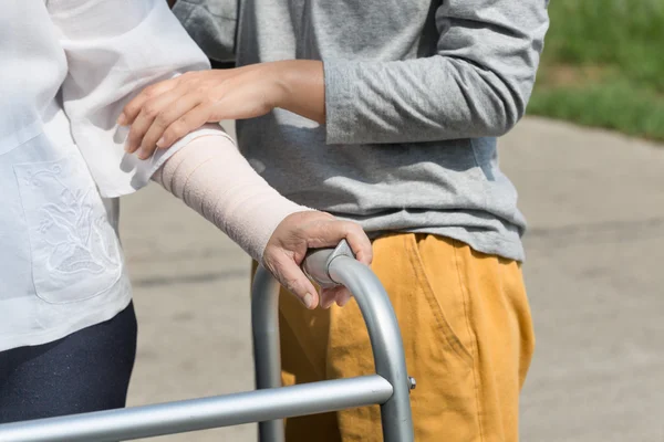 Mujer mayor usando un andador con cuidador para llevar ambulancia — Foto de Stock