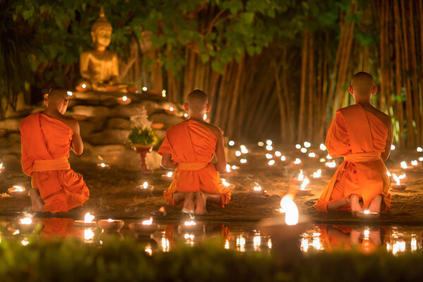 Asalha Puja Day ,Monks light candles to buddha statue ,Chiang mai.