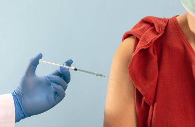 Doktor klinikteki kadına aşı yapıyor.