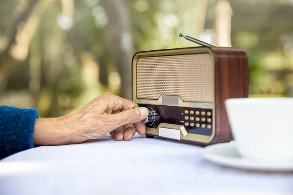 后院里的老年妇女手打开老式收音机的旋钮 — 图库照片