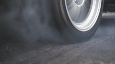 Sürüklenen yarış arabası yarışa hazırlanırken lastiklerini yakıyor.