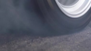 Sürüklenen yarış arabası yarışa hazırlanırken lastiklerini yakıyor.