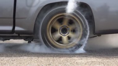 Sürüklenen yarış arabası yarışa hazırlanırken lastiklerini yakıyor.