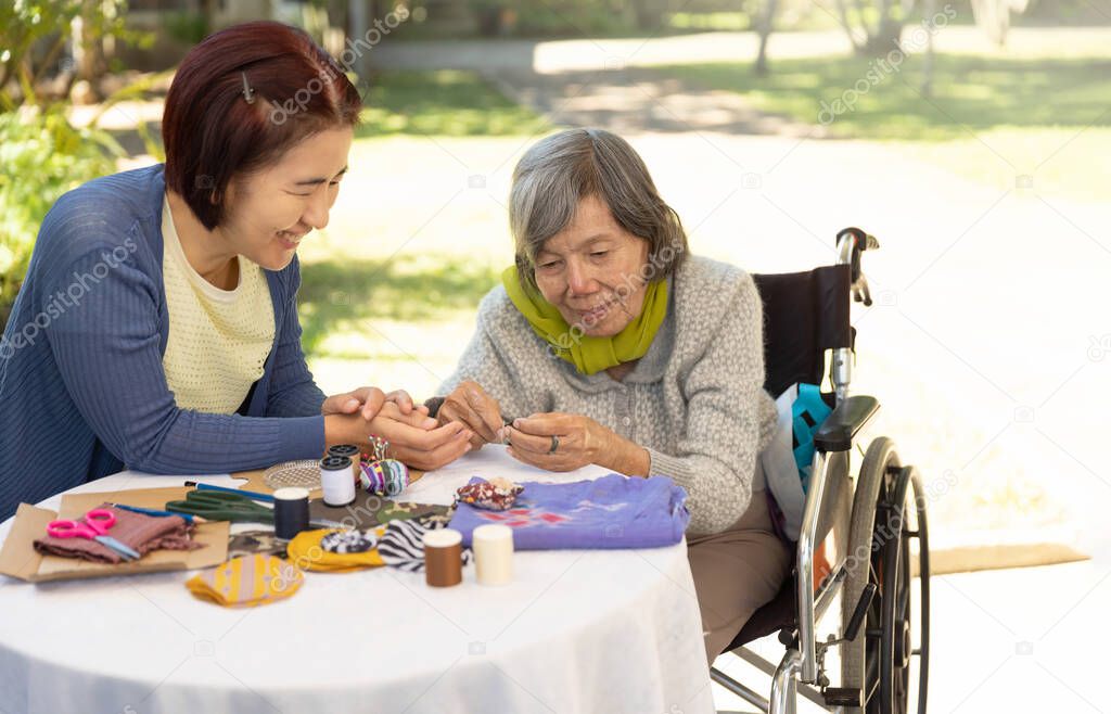 Elderly woman and daughter in the needle crafts occupational therapy for Alzheimer or dementia