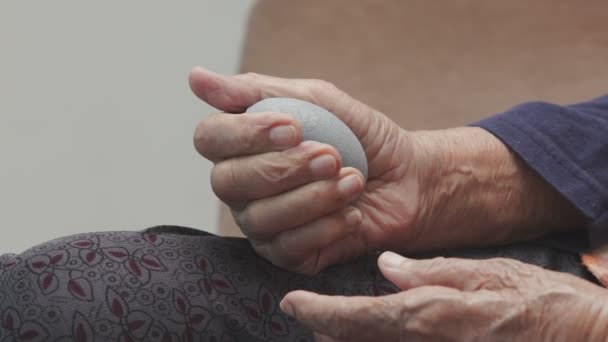 介護者と運動指 手のひら 手と足の筋肉のためのゴムボールを行う高齢女性が世話をする — ストック動画