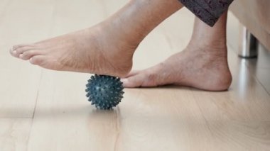 Egzersiz yapmak için lastik top oynayan yaşlı bir kadın. Parmaklar, el ve ayak kası. Bakıcıya dikkat et..