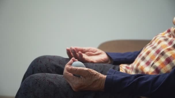 介護者と運動指 手のひら 手と足の筋肉のためのゴムボールを行う高齢女性が世話をする — ストック動画