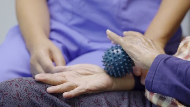 在护理人员的照料下 为锻炼手指 手足肌肉而做橡皮球的老年妇女要小心 — 图库视频影像