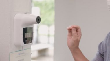 Kadın turist restorana girmeden önce duvar kızılötesi termometresi kullanıyor