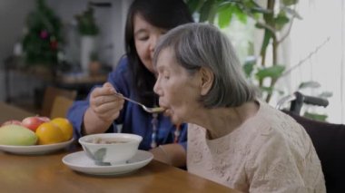 Yaşlı anneyi çorbayla besleyen kız.