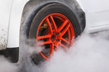 Drag racing car burns rubber off its tires in preparation for the race clipart