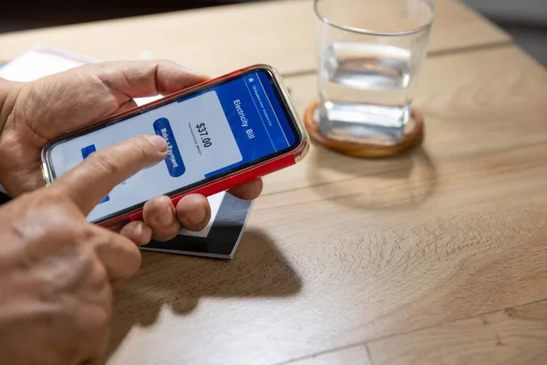 Cep telefonuyla elektrik faturasını ödemeye çalışan kafası karışmış yaşlı adamın elini kapat.