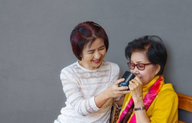 Asyalı orta yaşlı kız, yaşlı anneyi evde ağırlıyor.