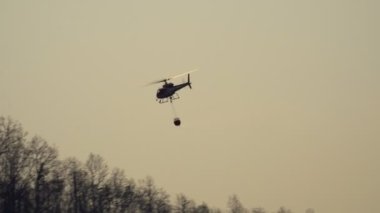 Yangın söndürme helikopteri orman yangınına su bırakıyor.