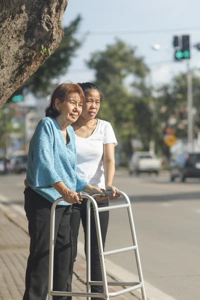 Senior vrouw met behulp van een walker cross street. — Stockfoto