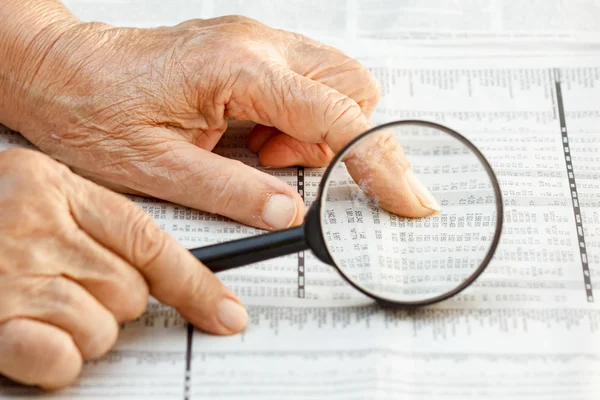 Senior mujer leyendo listados de acciones — Foto de Stock