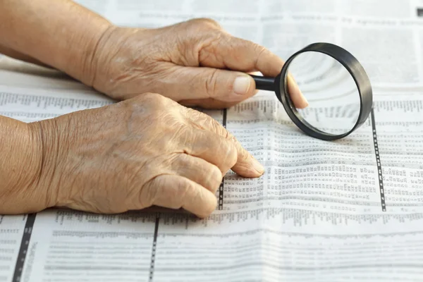 Äldre kvinna läsande lager listor — Stockfoto