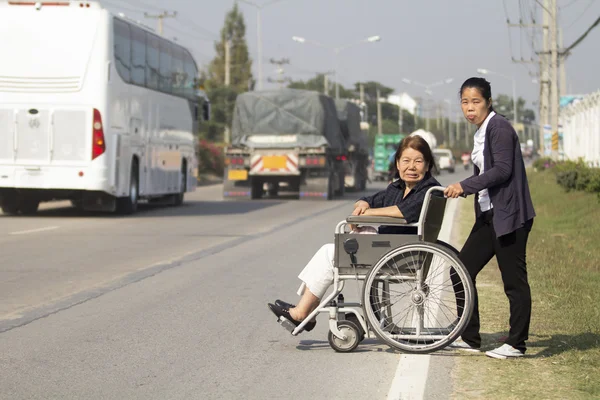 Senior vrouw met behulp van een rolstoel cross street — Stockfoto