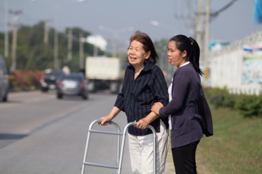 Senior woman using a walker cross street clipart