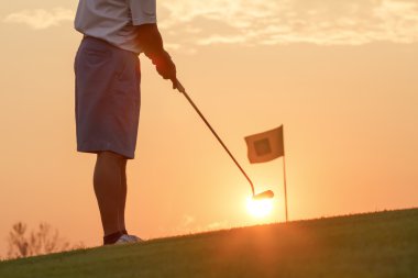 Golf topu günbatımı karşı koyarak adam