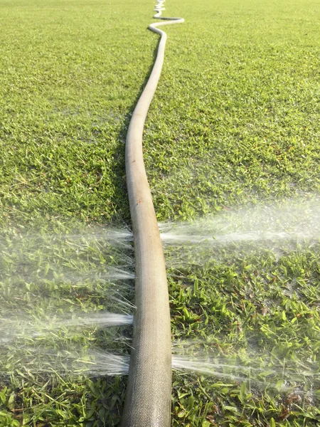 Wasser verschwenden - Wasser, das aus einem Loch in einem Schlauch austritt — Stockfoto