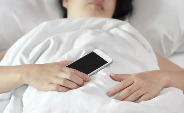 Woman sleeping in bed and holding a mobile phone. — Stock Photo, Image