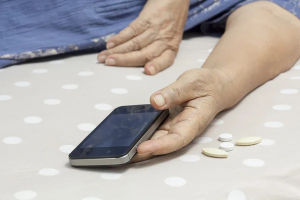 Oudere vrouw slapen in bed en houden van een mobiele telefoon. — Stockfoto