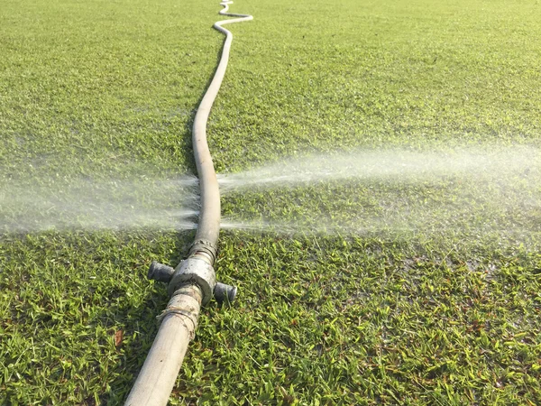 Wasting water - water leaking from hole in a hose — Stock Photo, Image