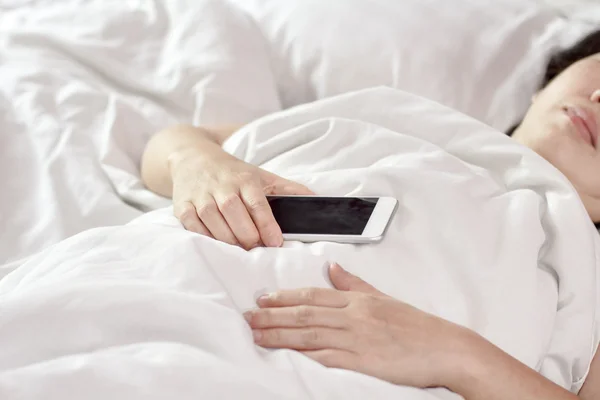 Woman sleeping in bed and holding a mobile phone. — Stock Photo, Image